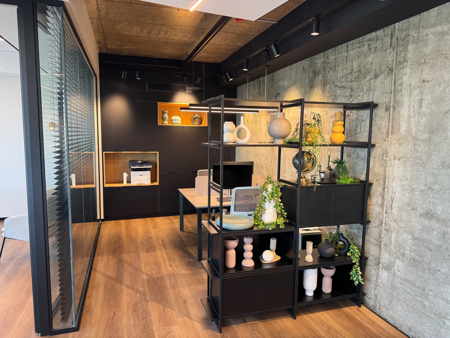 An office corner with warm lighting, shelving and plants